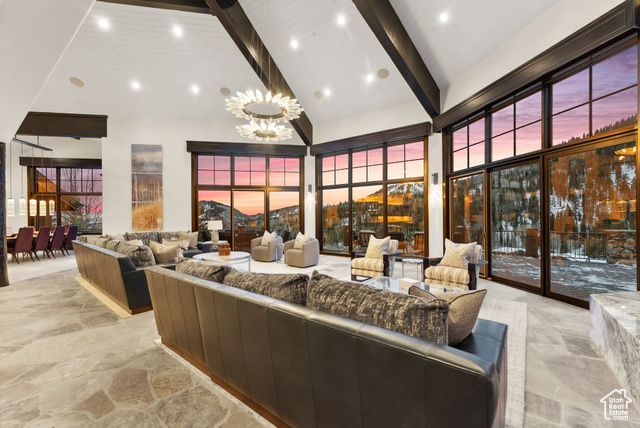 Living room featuring beam ceiling, high vaulted ceiling, and a notable chandelier