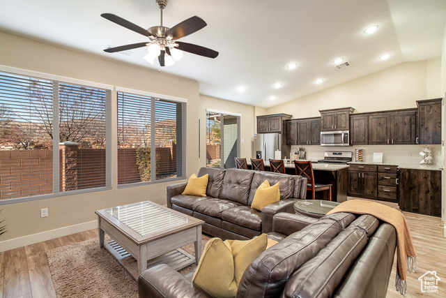 Living room with ceiling fan, light wood-type flooring, and lofted ceiling