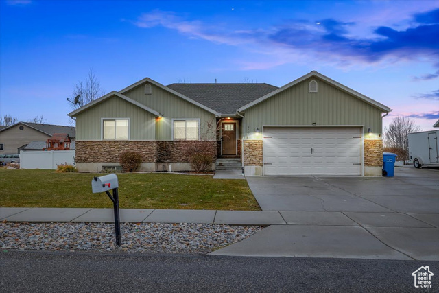 Ranch-style home with a garage and a yard