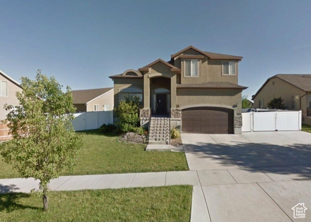 View of front facade featuring a garage and a front lawn