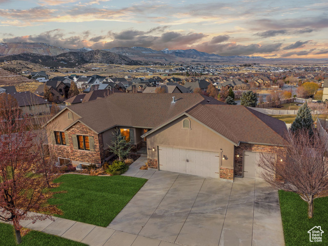 View of front of house featuring a mountain view, a yard, and a garage