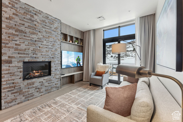 Living room with built in shelves, a fireplace, and light wood-type flooring