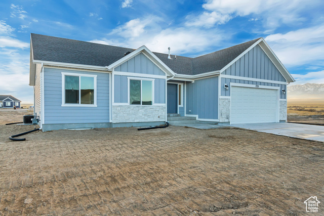 View of front of property featuring a garage and central air condition unit