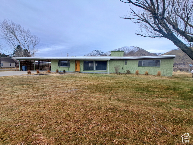 View of front of property featuring a mountain view, a front lawn, and a carport