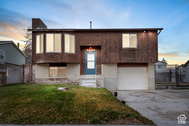 View of front of property with a yard and a garage