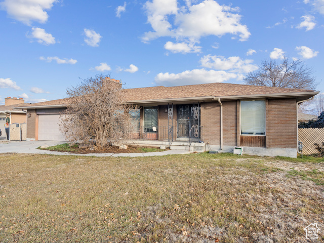 Single story home with a garage and a front lawn