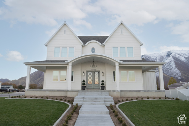 View of front of house featuring a mountain view, a front lawn, and covered porch