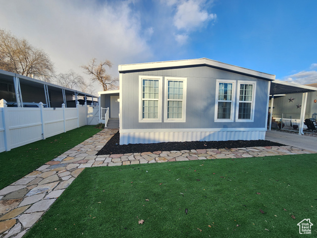 View of property exterior with a lawn and a carport