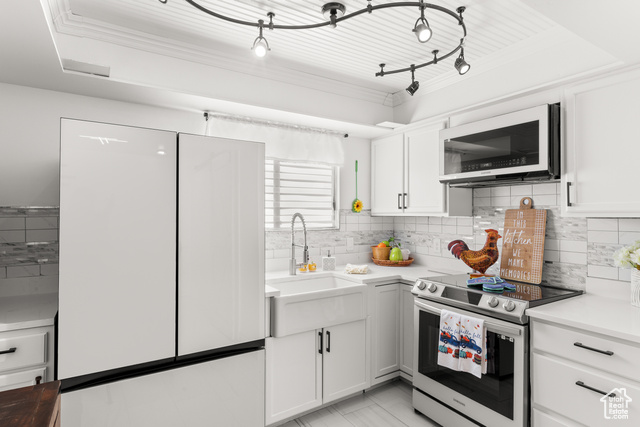 Kitchen with stainless steel range with electric cooktop, white cabinets, sink, tasteful backsplash, and white fridge