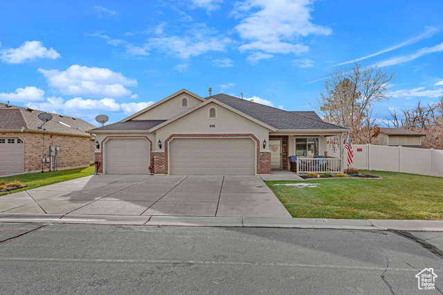 Ranch-style home with a front lawn, a porch, and a garage