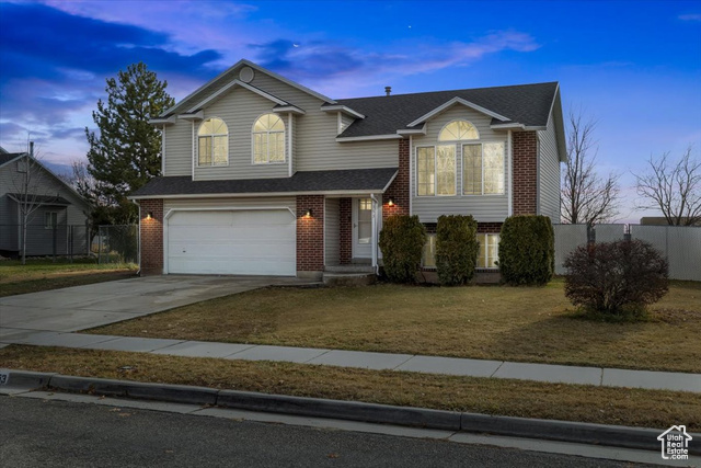 View of front facade featuring a lawn and a garage