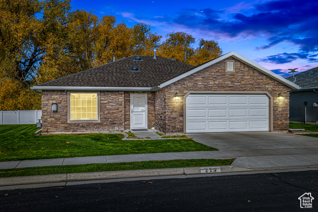 Single story home featuring a lawn and a garage