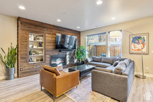 Living room with a large fireplace, wooden walls, and light hardwood / wood-style flooring