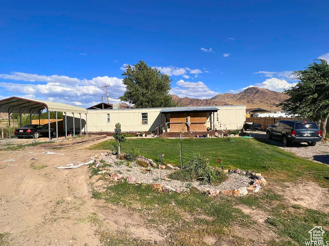 Exterior space with a mountain view, a front yard, and a carport