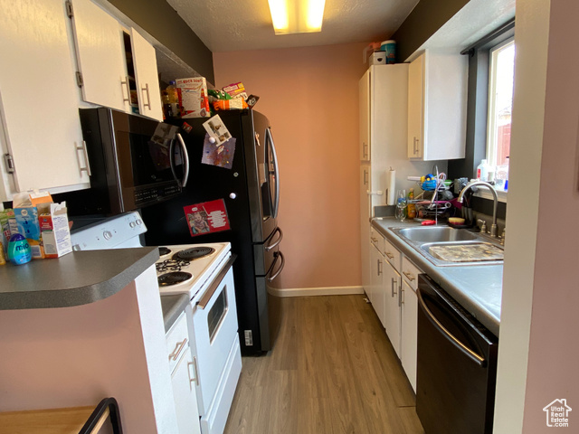 Kitchen with dishwashing machine, electric stove, white cabinetry, and sink