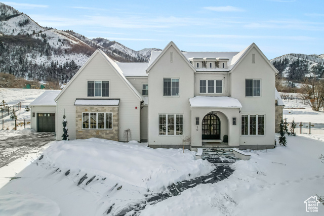 Snow covered house with a mountain view and a garage