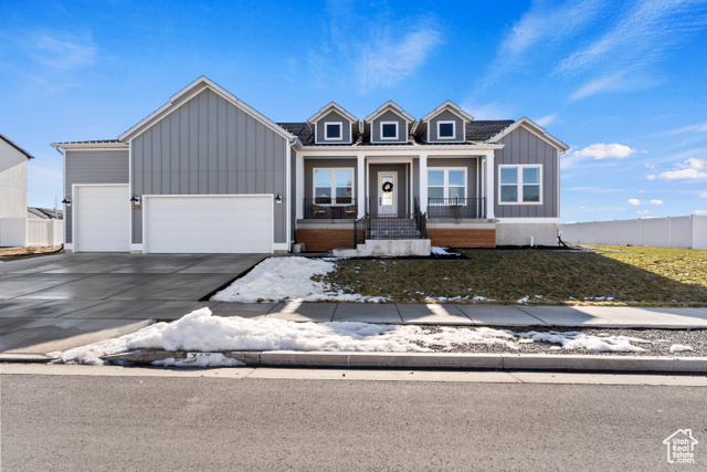 View of front facade featuring a front lawn, covered porch, and a garage