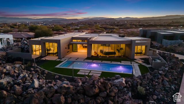 Back house at dusk featuring a mountain view and a patio area