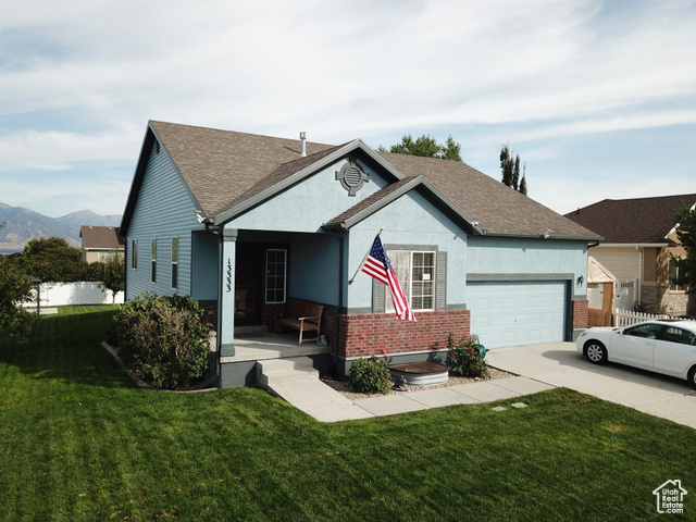 View of front of house with covered porch, a garage, and a front lawn