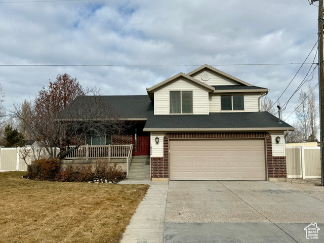 View of front of property featuring a front yard, a porch, and a garage