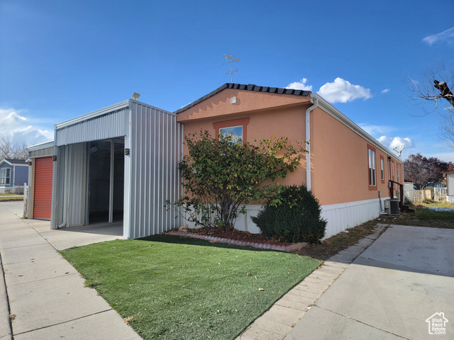 View of property exterior with a yard and central AC