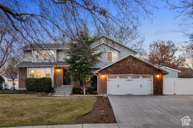 View of front facade featuring a garage and a yard