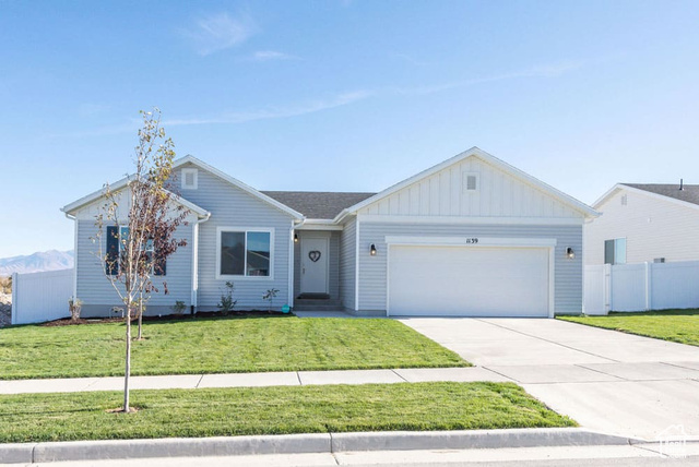 Ranch-style house with a garage and a front lawn