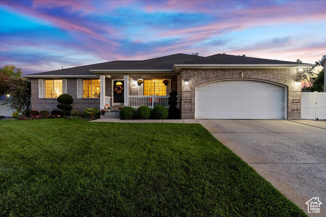 Ranch-style home featuring a lawn and a garage