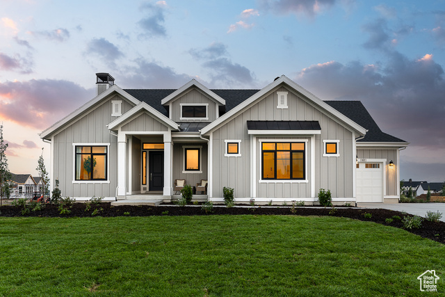 View of front of house featuring a porch, a garage, and a lawn