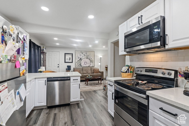 Kitchen featuring white cabinets, backsplash, and stainless steel appliances