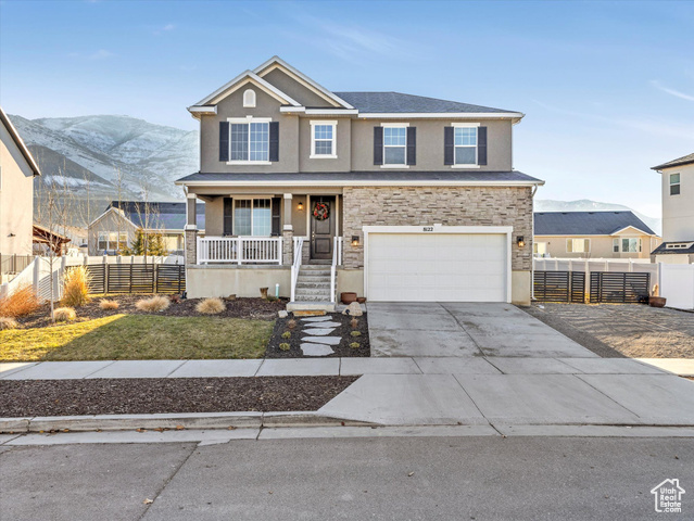 View of front of property with a mountain view, covered porch, a front yard, and a garage