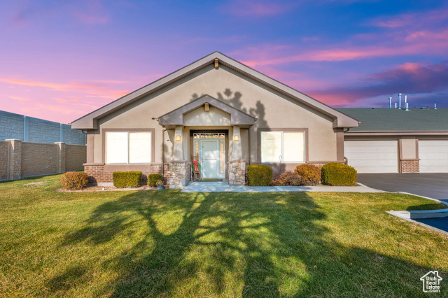 Ranch-style home featuring a garage and a lawn