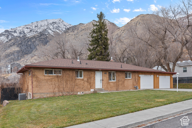 View of front of house featuring a mountain view, a front lawn, and garage space for 2 cars