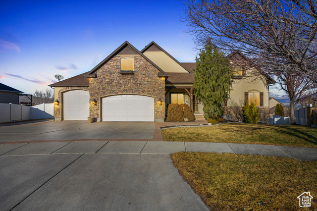 View of front of property featuring a 3 car garage and a lawn