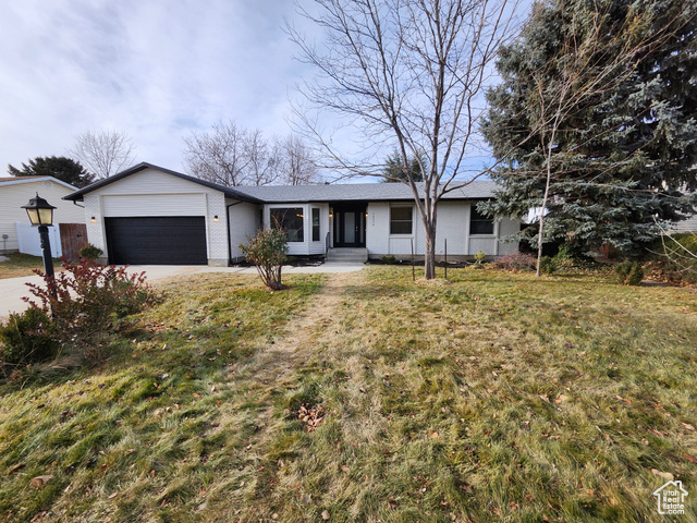 Single story home featuring a garage and a front lawn