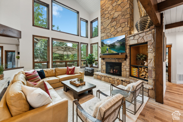 Living room with plenty of natural light, a fireplace, high vaulted ceiling, and light hardwood / wood-style flooring