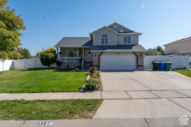 View of front of house featuring covered porch, a front yard, and a garage