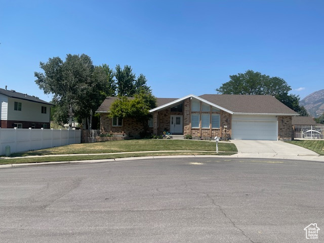 View of front of home featuring a mountain view, a front lawn, and a garage