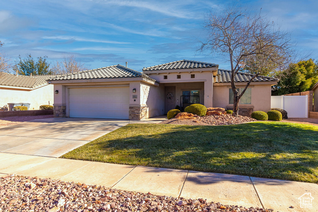 Mediterranean / spanish-style home featuring a garage and a front lawn