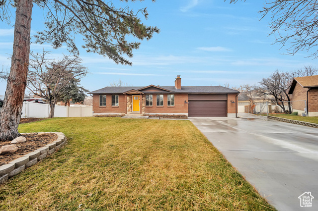 Ranch-style house with a garage and a front lawn