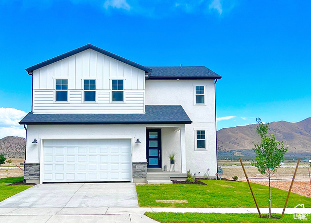 View of front of property featuring a mountain view, a front yard, and a garage