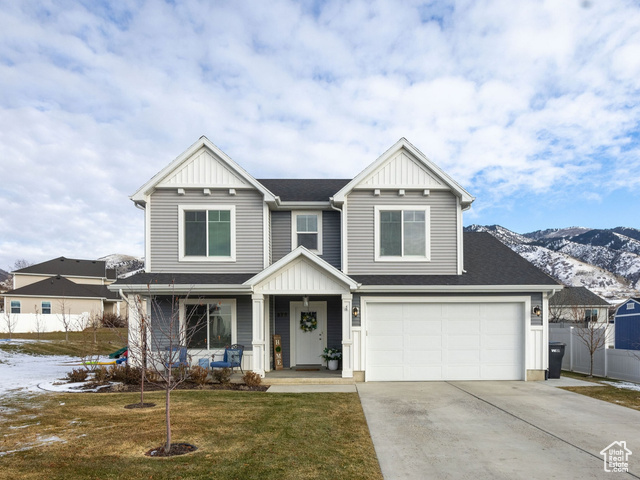 View of front facade with a mountain view, a yard, a porch, and a garage