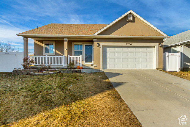 View of front of house featuring a front yard, a porch, and a garage