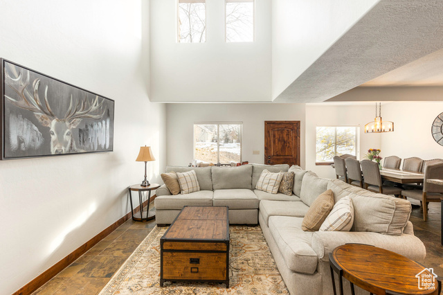 Living room featuring a healthy amount of sunlight, a high ceiling, and an inviting chandelier