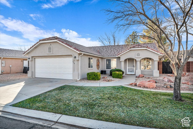 View of front of property featuring a garage and a front lawn