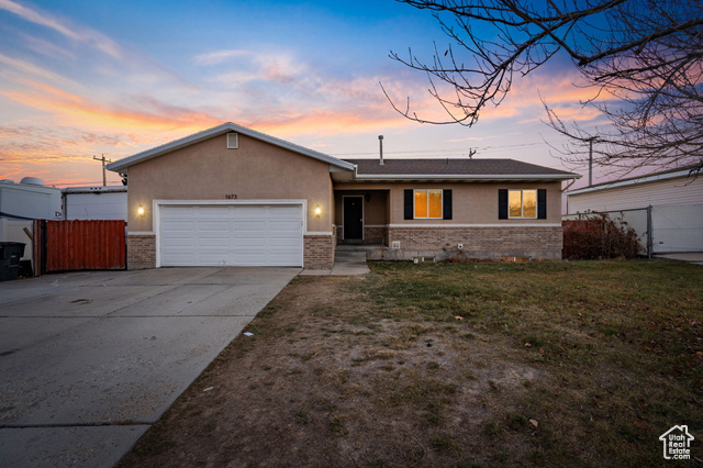 Single story home featuring a lawn and a garage