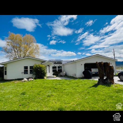 Rear view of house with a lawn, solar panels, and a garage