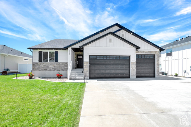 Modern farmhouse style home featuring a garage and a front yard