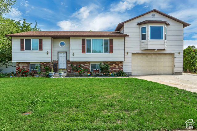 View of front of property featuring a garage and a front lawn