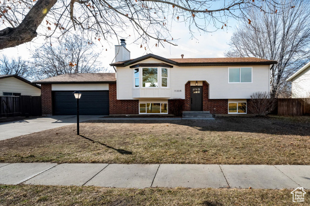 Split foyer home with a garage and a front yard